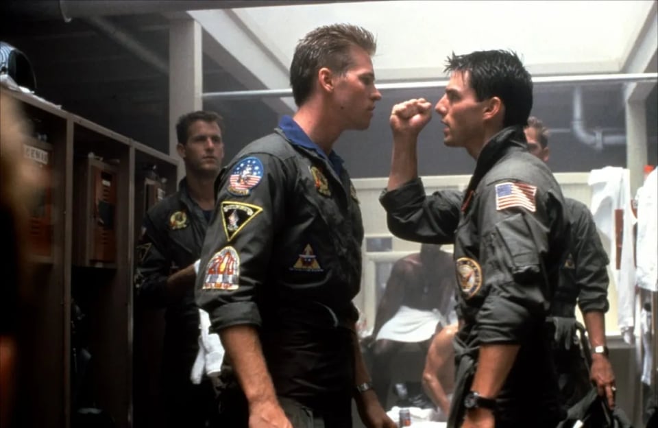 Iceman (Val Kilmer) confronts Maverick (Tom Cruise) in Top Gun while the other pilots look on.