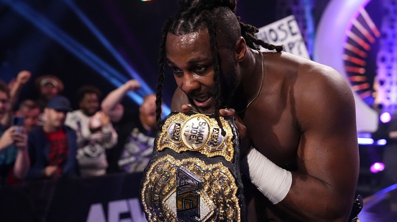 Swerve Strickland holding the AEW World Championship belt to his chest after winning it from former champion Samoa Joe.