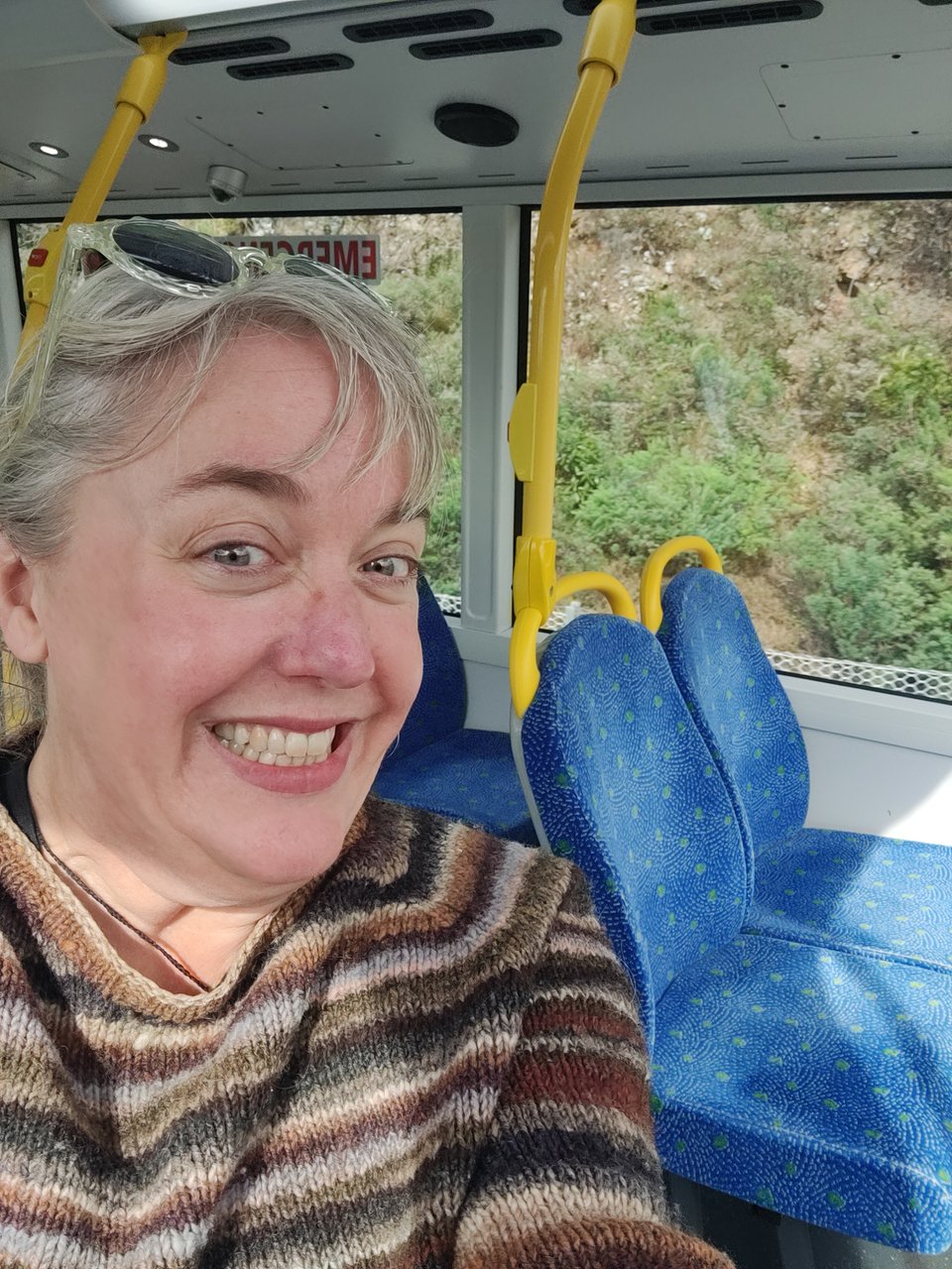 picture of Rachael on the top deck of a double decker bus, no one else near her - she's smiling REALLY big
