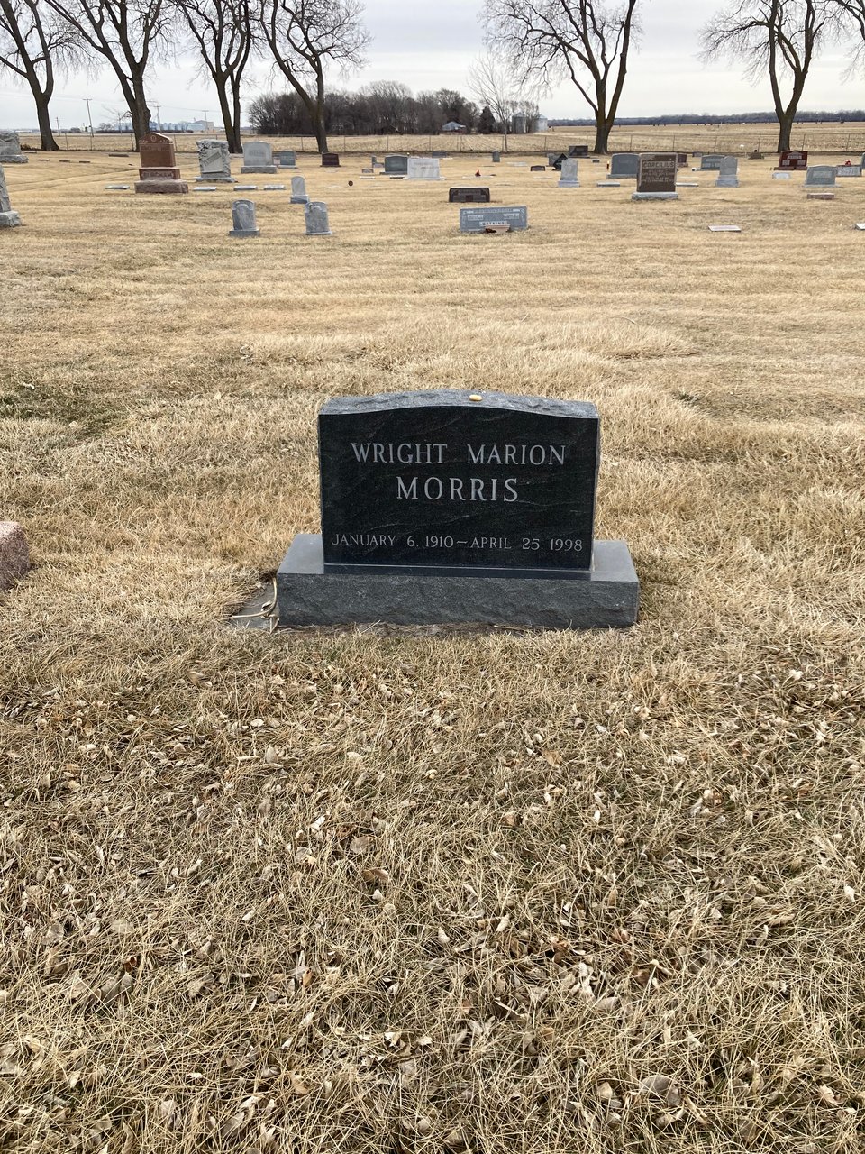An image of Wright Morris's headstone in the graveyard in Chapman, Nebraska. A simple black marker reading "Wright Marion Morris, January 6, 1910-April 25, 1998"