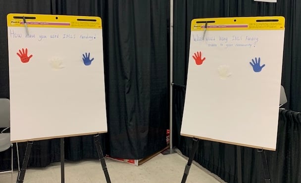 Two large sticky note sheets inside the otherwise empty IMLS booth at the Association for Rural and Small Libraries conference.