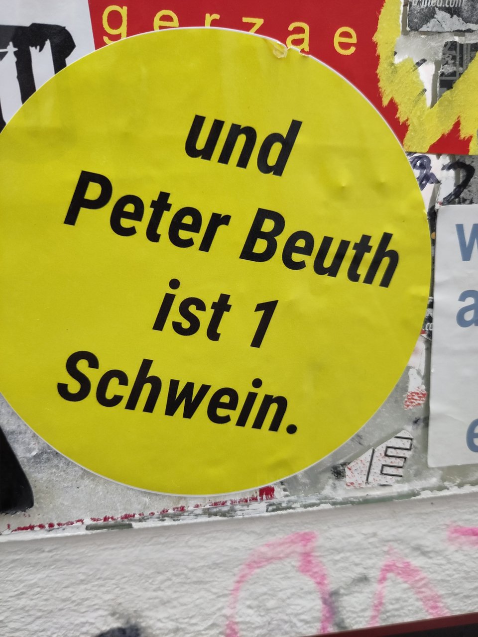 Ein runder gelber Aufkleber auf dem steht: "und Peter Beuth ist ein Schwein."