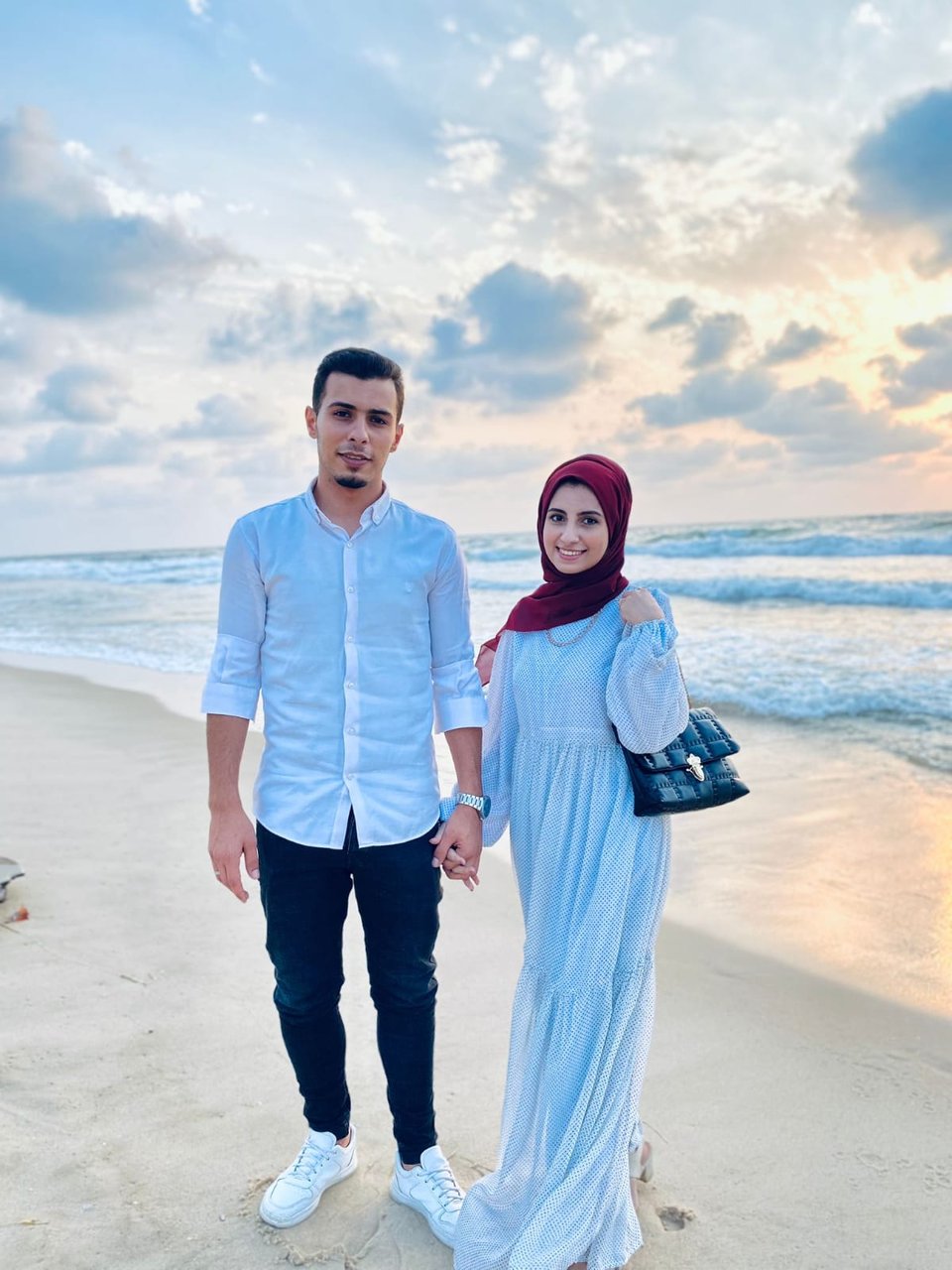 Ahmad and his fiancée Samar, holding hands on a beach at sunset.