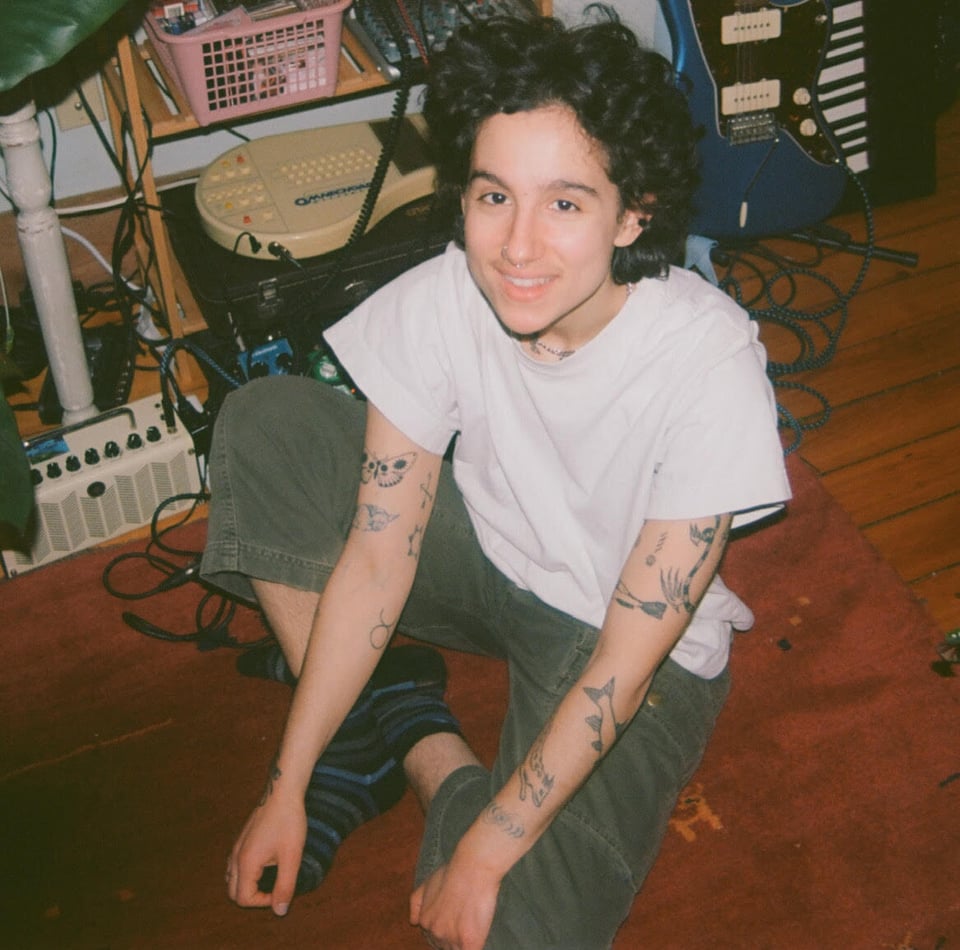 Northampton musician bobbie sits on the floor, looking up at the camera.