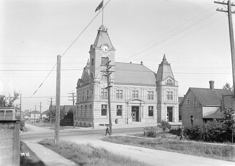 Image of a large post office building with a clock tower an arched entrance and several windows.