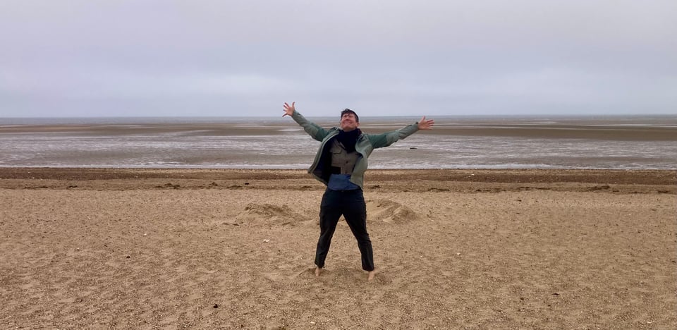 Lucy with her arms thrown wide in front of the steely Norfolk sea.