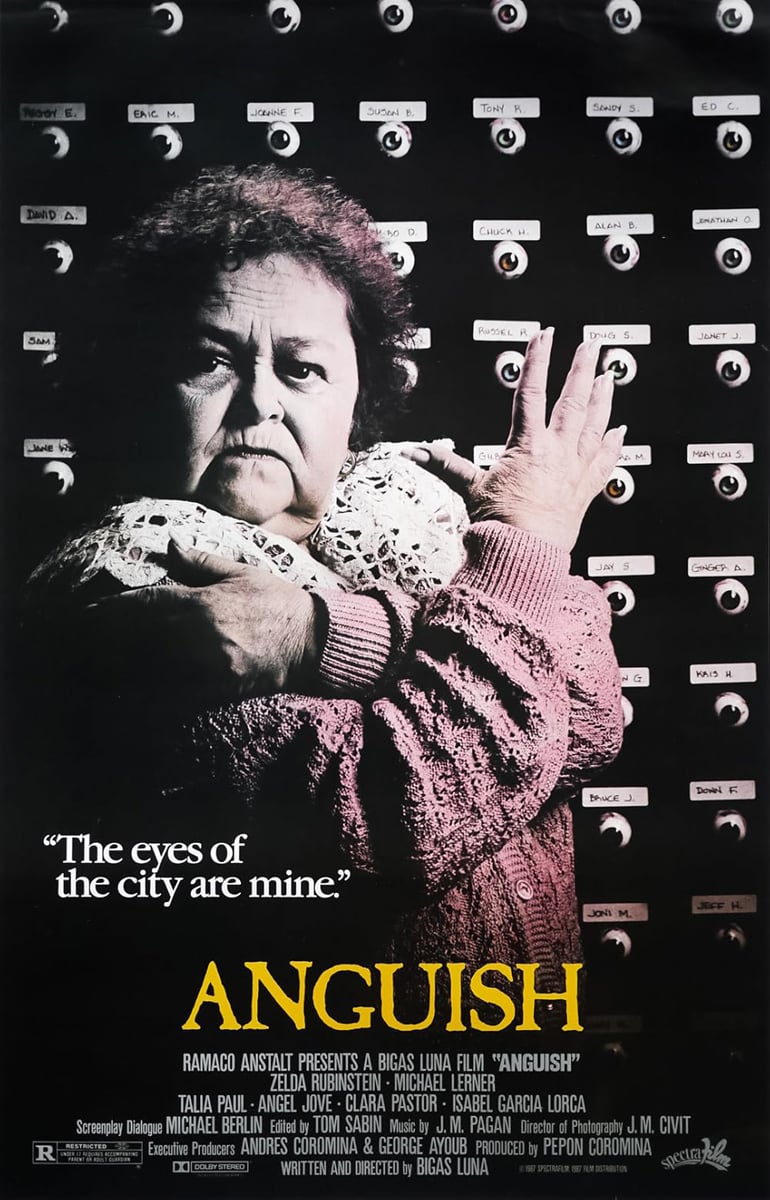 A promotional poster for the Bigas Luna film Anguish, featuring Zelda Rubenstein in a pink cardigan standing in front of a wall of eyes, each with a little handwritten name label above. "The eyes of the city are mine," she says.