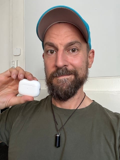 Some dingus astrologer holding an AirPod case, looking pretty smug and self-satisfied.