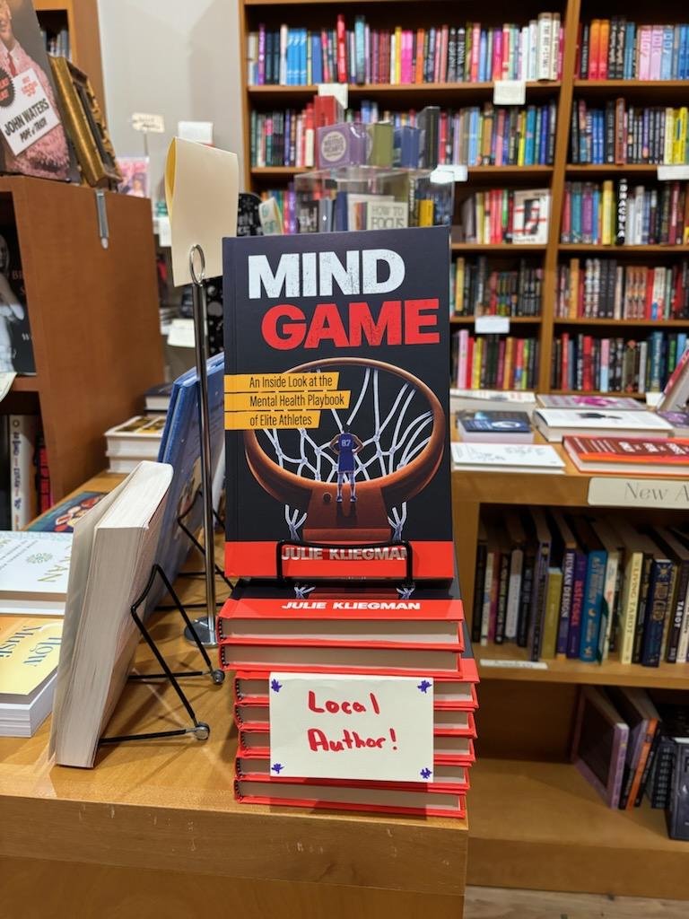 A stack of Mind Game copies at Astoria Bookshop with a local author sign