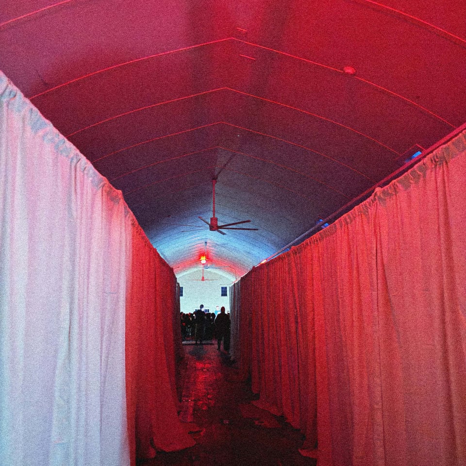 a long barn, darkness and drapery bathed in red exit sign lighting