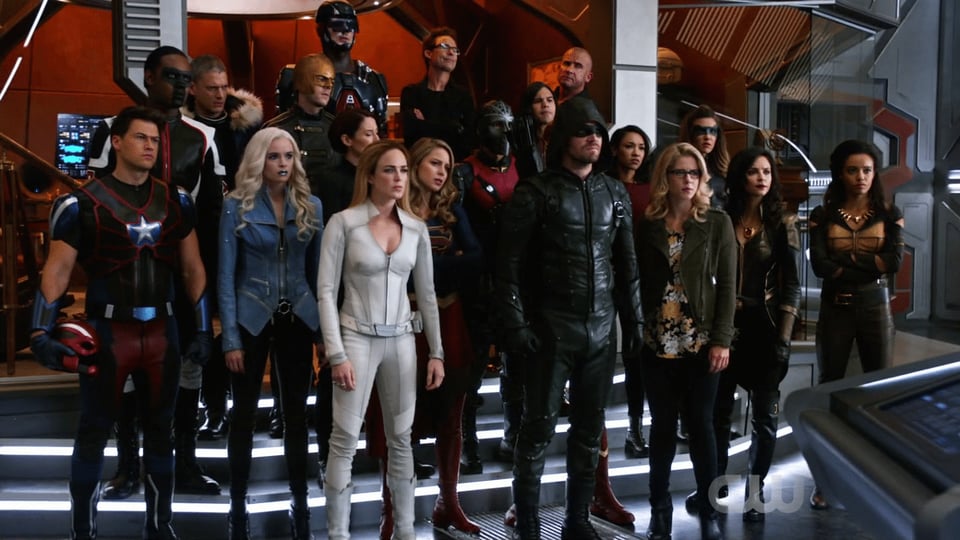 A group shot showing characters from Arrow, The Flash, Supergirl and Legends of Tomorrow on board the Waverider.