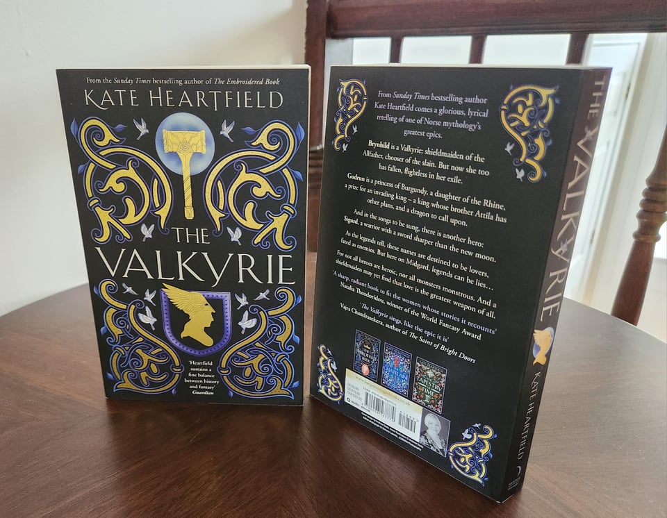 Two paperback copeis of The Valkyrie, one showing the front cover and one the back. It's black with gold and purple Norse elements.