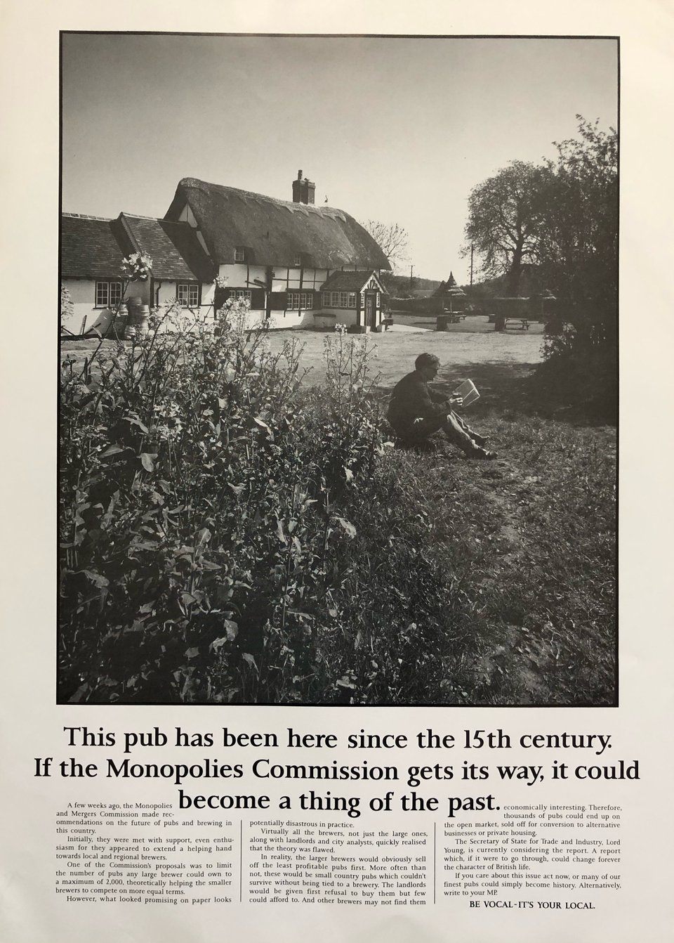 A newspaper advert. The main image is a black and white photograph of a quaint pub with a thatched roof. In the foreground, a man is sitting on the grass reading a book whilst enjoying a beer. The headline reads,