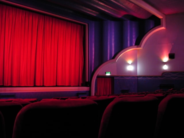 A cinema screen to the left, with a huge moderne proscenium arch. The arch includes huge wave or cloud like curves.
