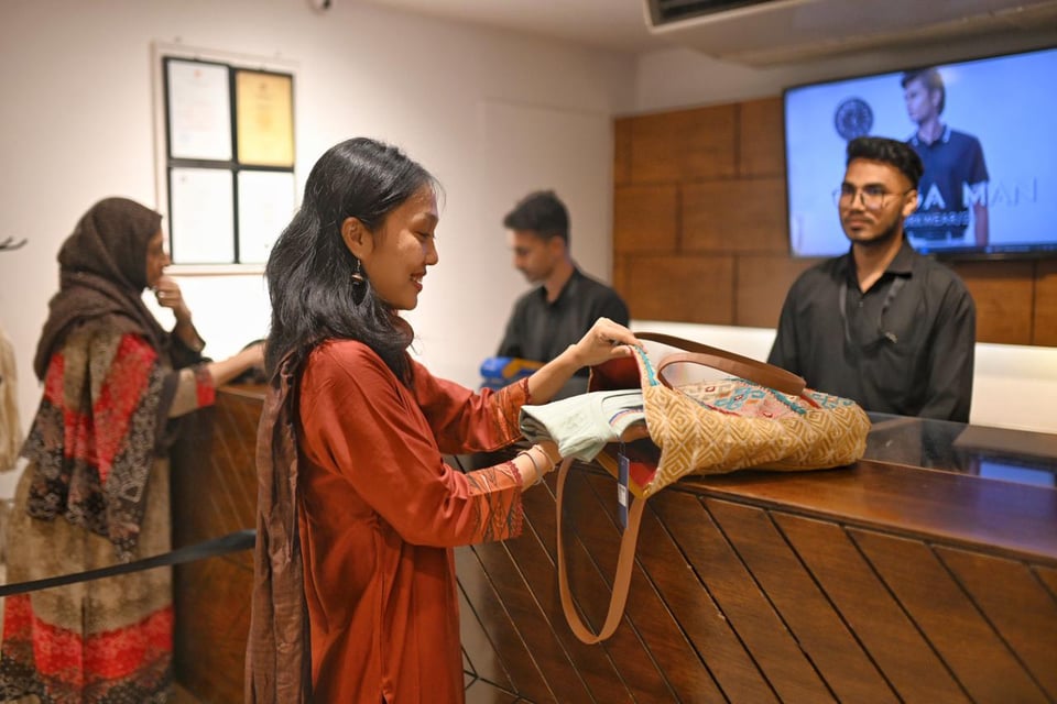 A woman places clothes she bought at a clothing store in a reusable bag