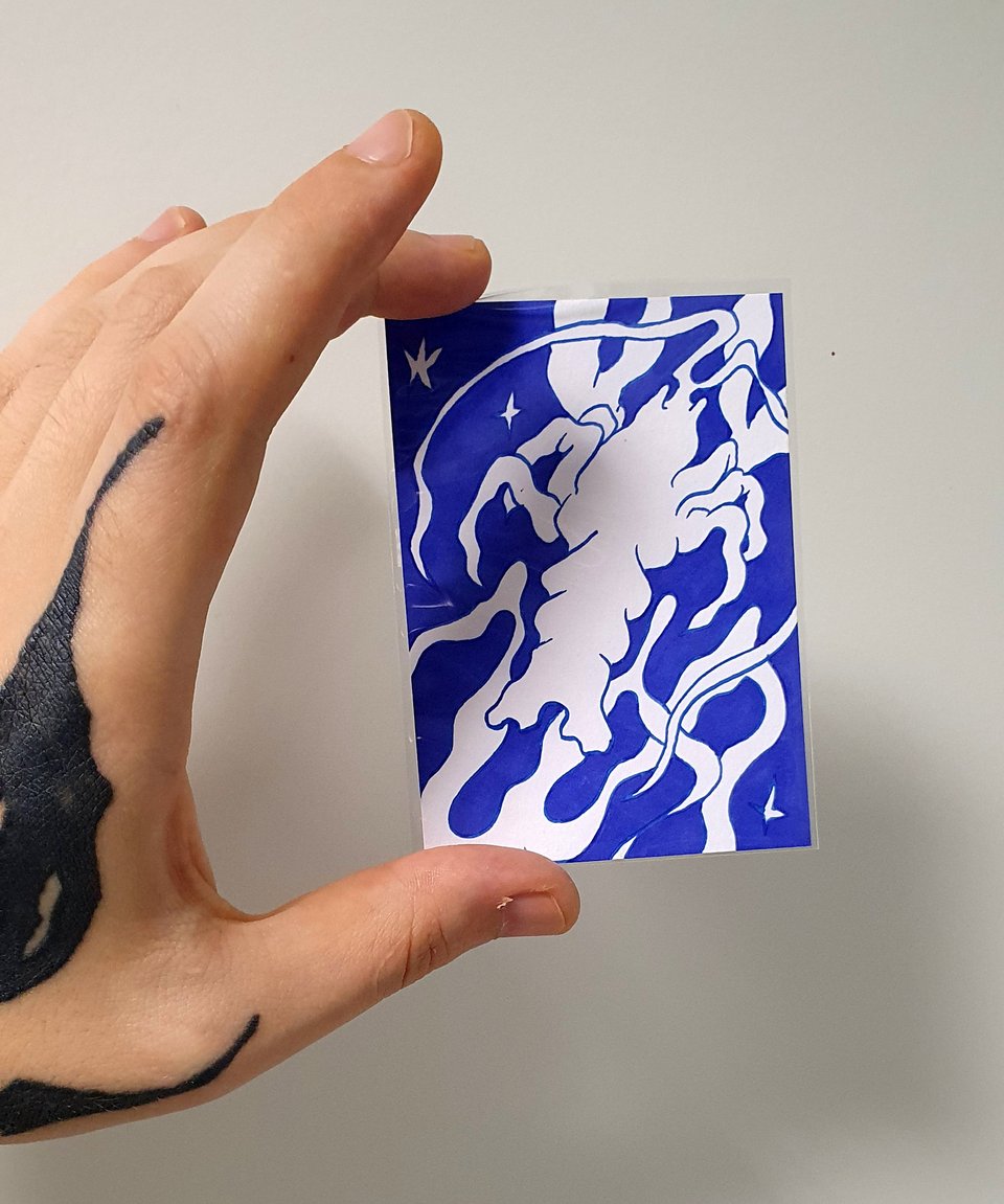 a hand holding a small sized picture depicting a blue crustacean