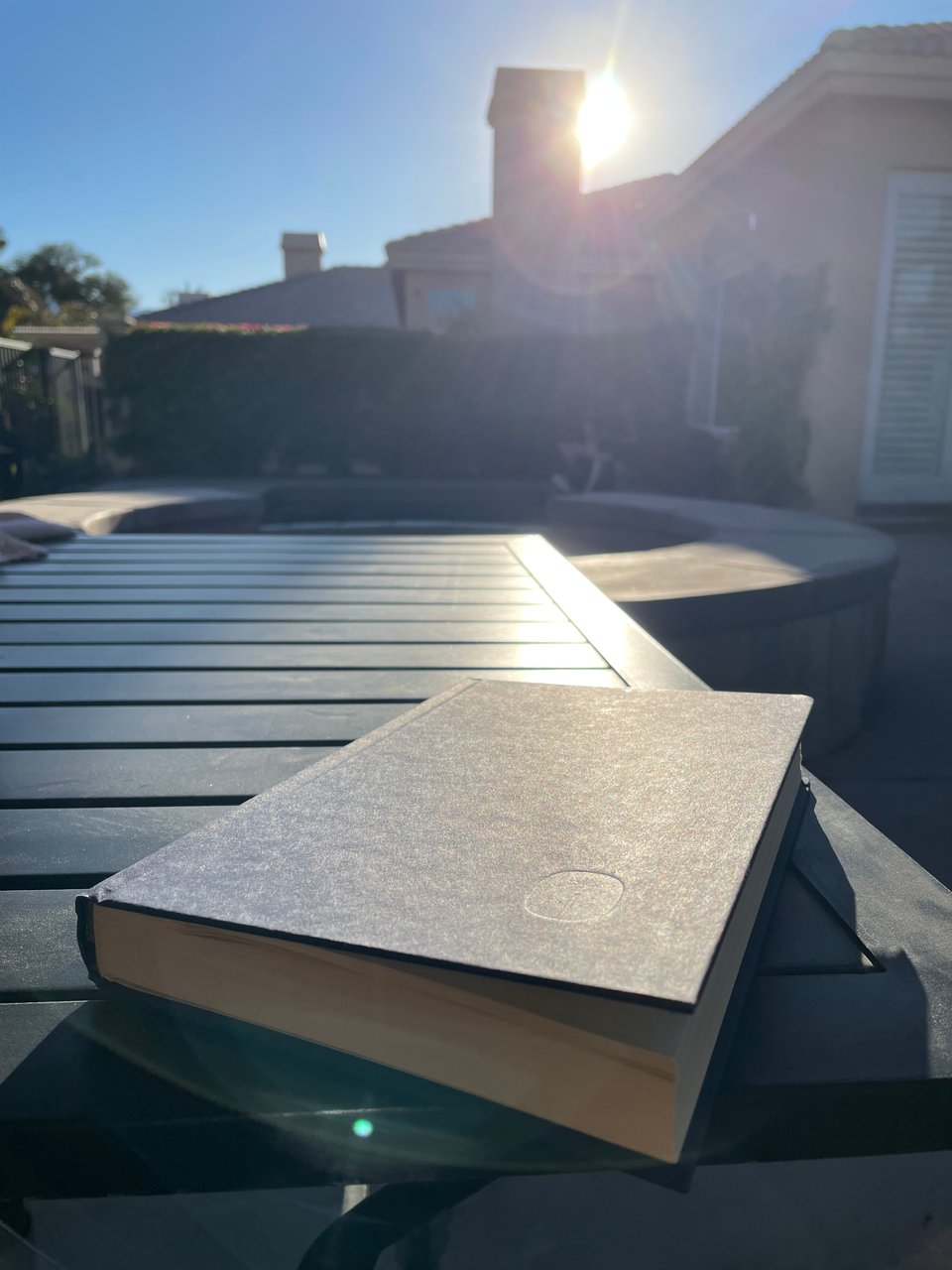 A book sits on a lawn table as the sun beams down