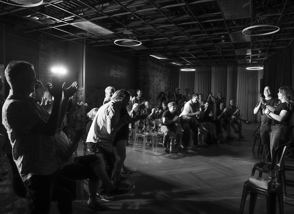A black and white image of an audience applauding Vinny and Katie after their show