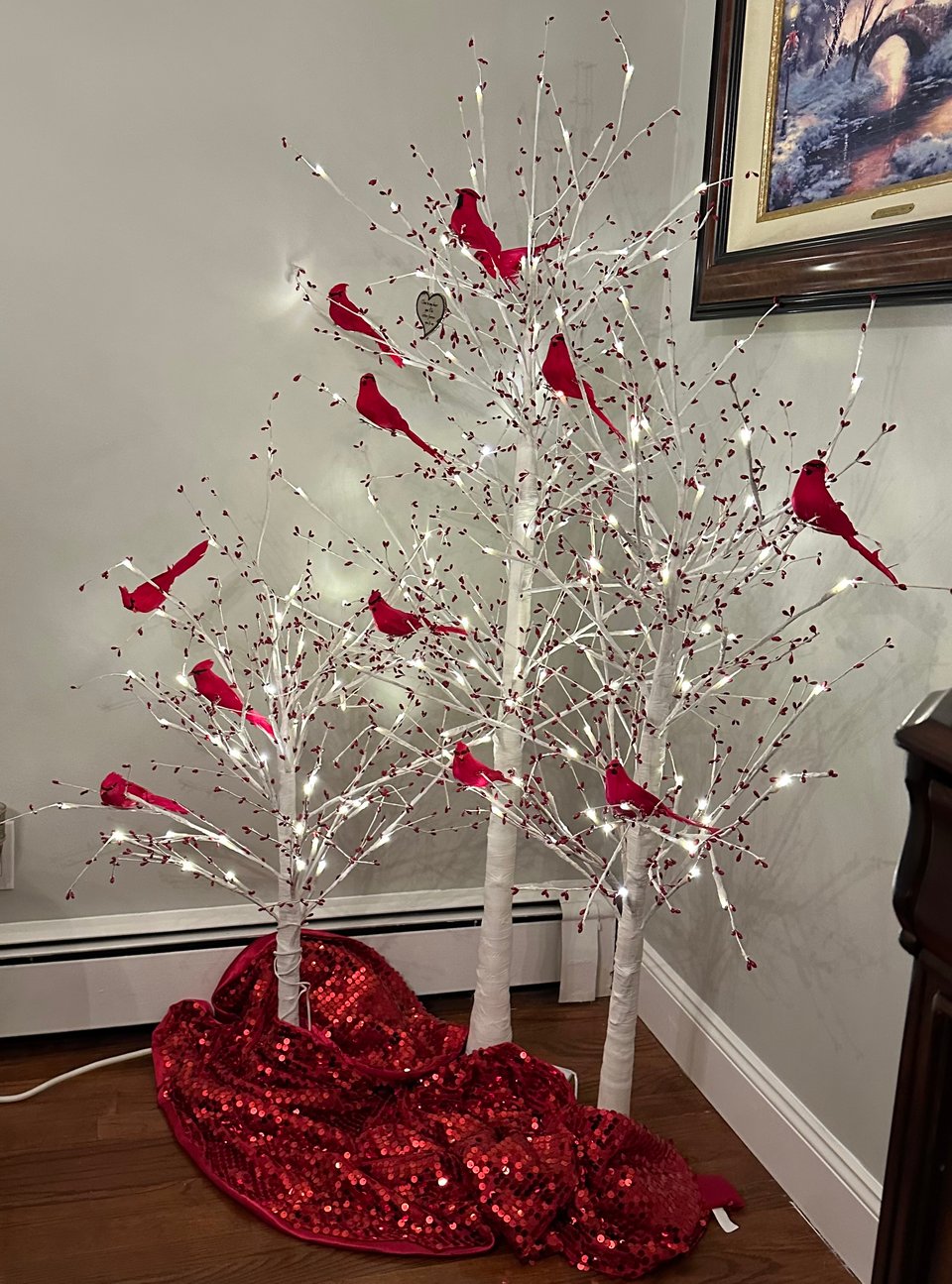 Christmas decoration: three artificial white trees, festooned with lights and red buds, with a dozen red cardinals in the branches