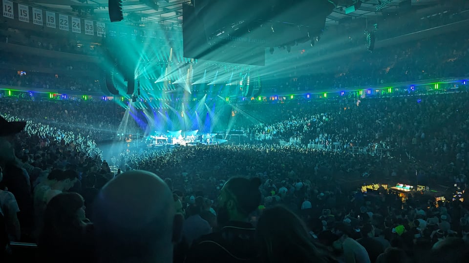 Blue and green hued photo of Phish performing in front of an audience at Madison Square Garden