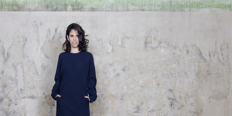 Inbal Lori in front of an industrial looking wall.