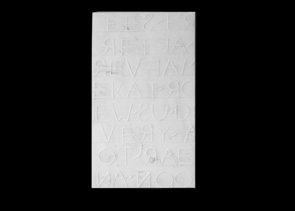 White letters on a white cover, with traces of graphite and smudge marks around the raised letterforms, reminiscent of a rubbing.