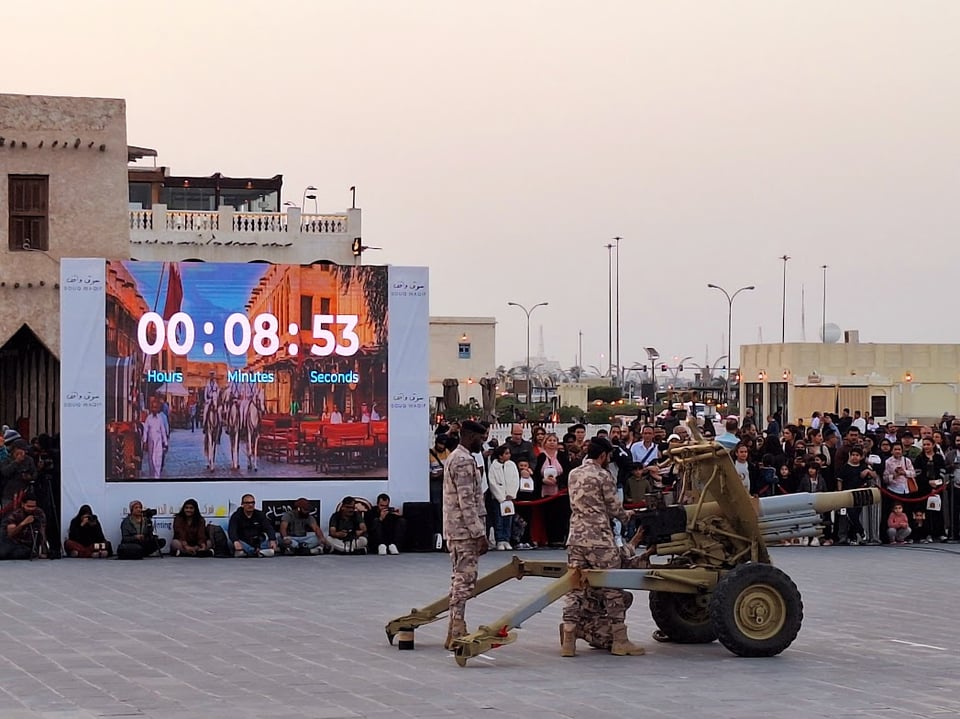 Soldiers preparing to fine the cannon. Crowd gathered. Countdown displayed on the screen.