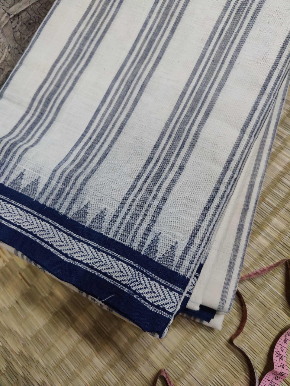 A white saree with blue stripes and a blue border with a white design and blue kuppadam.