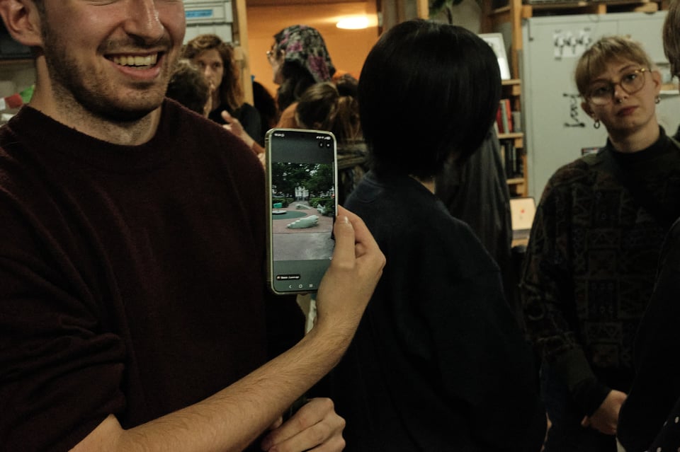 A man, laughing, shows a photo on his phone screen