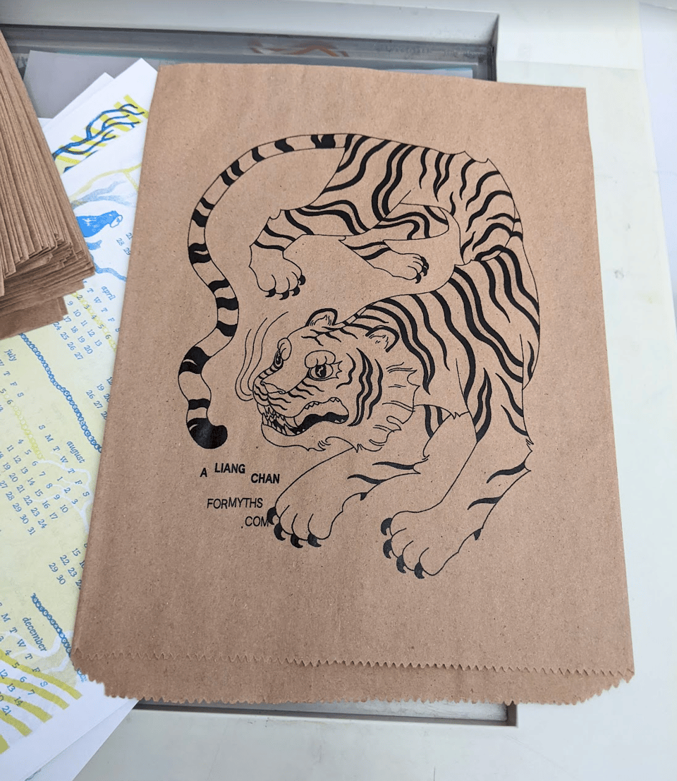 a twisting tiger design printed (upside down) on a kraft paper merch sleeve.