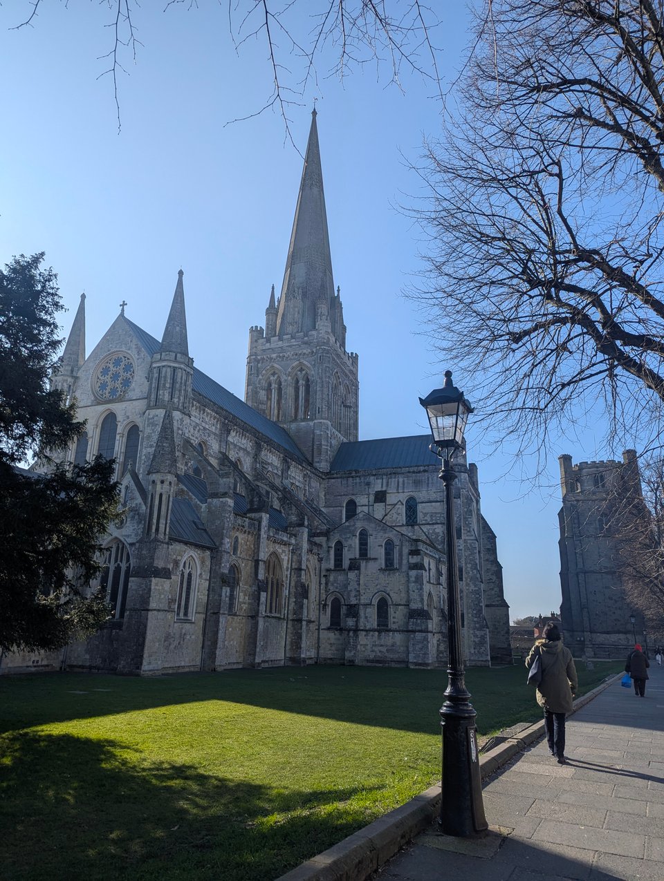 A Gothic cathedral with a tall spire and many flying buttresses, on a sunny day.