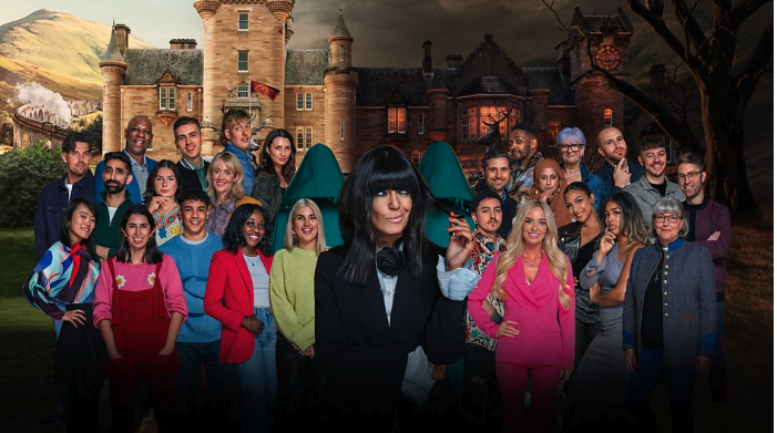 Screenshot showing Claudia Winkleman (host) and all the 22 contestants of Season 3 of The Traitors UK. In between everyone are two hooded figures, with their heads down.
