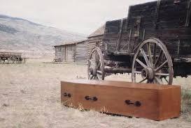 A coffin next to a wagon with the background the Wild West