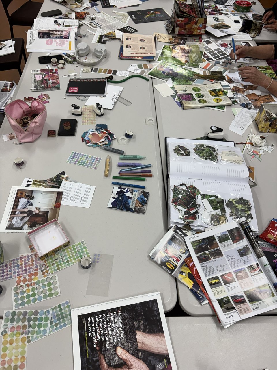 Bird's eye shot of a table of craft - anonymous participant arms and hands working on zines visible.