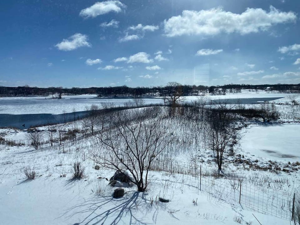 a snow covered field with a lake in the background