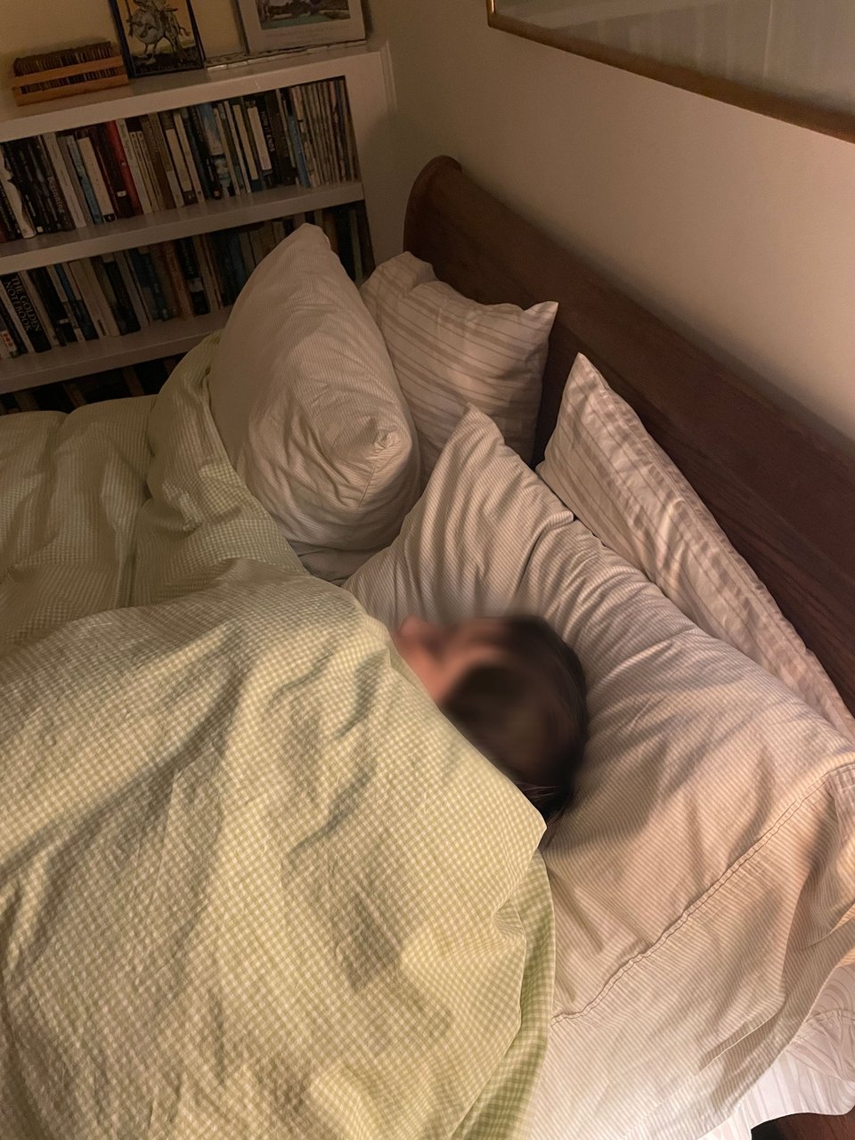 A young boy sleeps in a bed. His face is blurred.