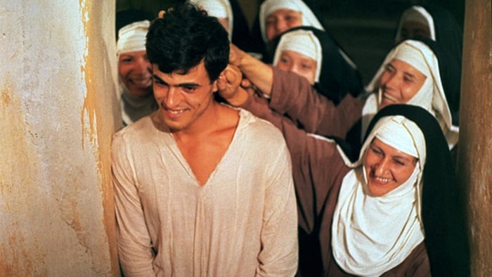 Still from a movie showing a young man smiling, surrounded by happy nuns