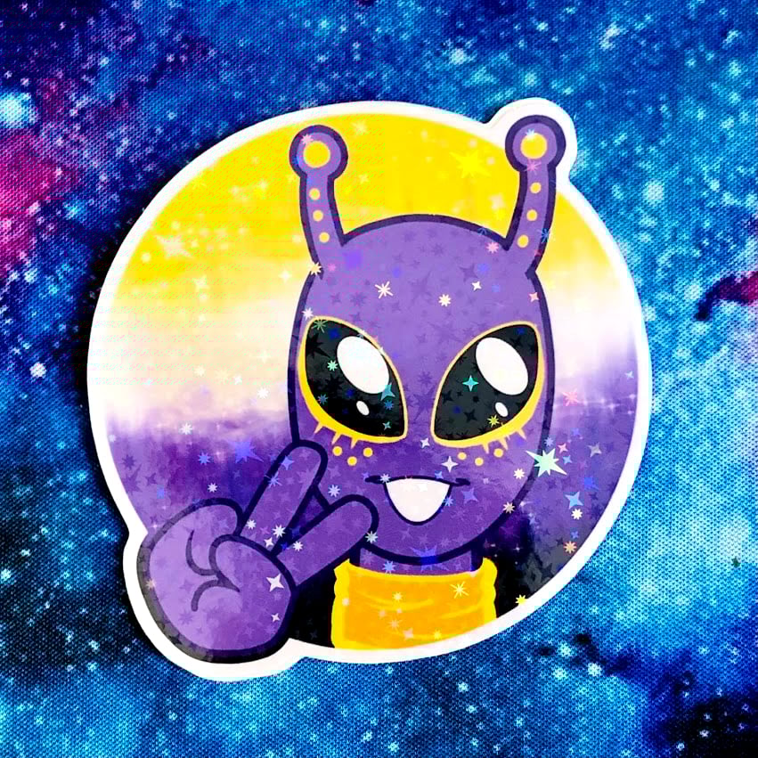 A sticker of a purple/gold alien making a peace sign in front of a nonbinary flag colored planet.