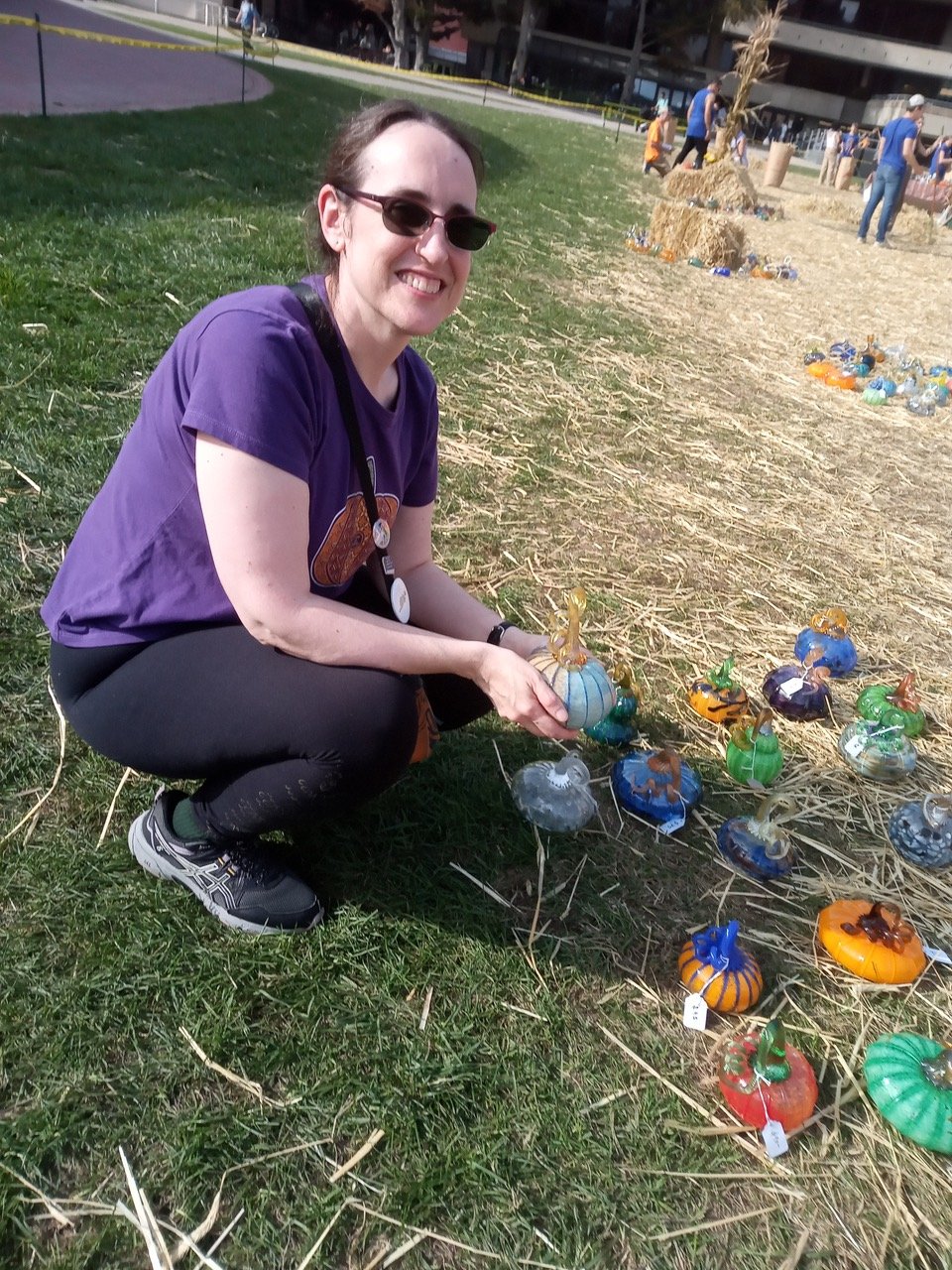 The author squatting next to some blown-glass pumpkins on the ground.