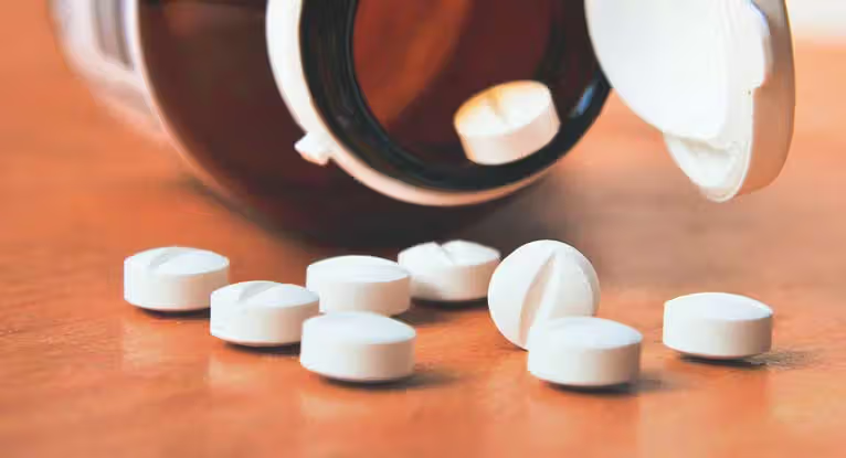 Bottle of pills that has spilled over onto a table.