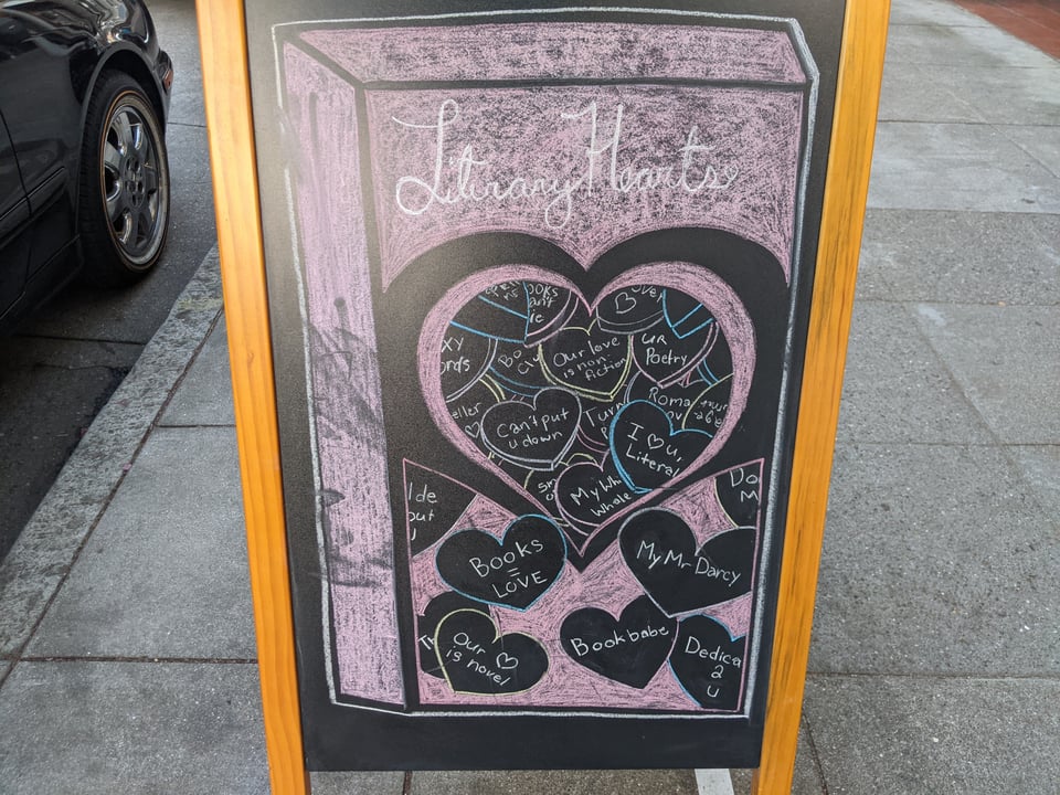 A chalk sign says Literary Hearts and then has a bunch of Valentines day type hearts saying Books = Love and  Book babe