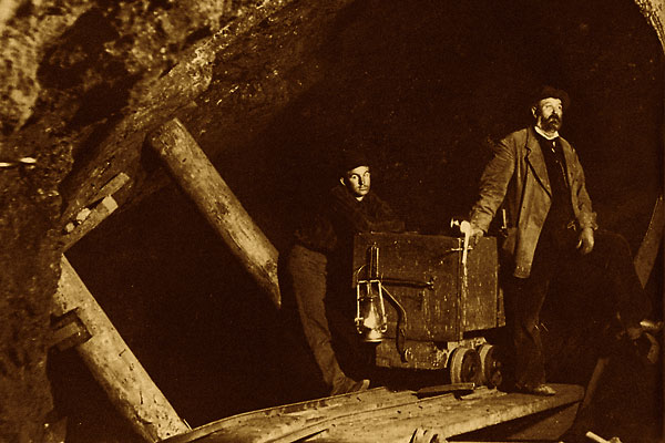 Two miners and a mine cart, in a mine.