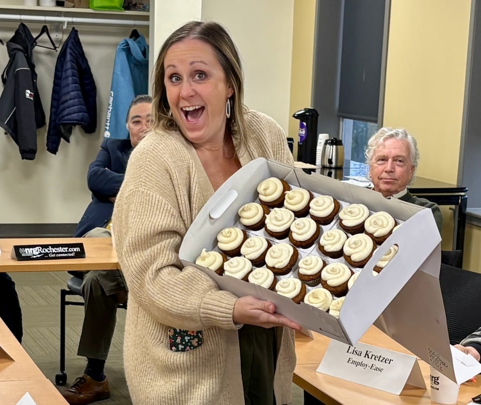 Holly holds a box of frosted cupcakes and has a big smile on her face.