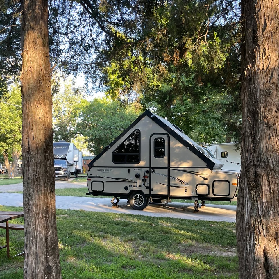 a small camper parked in a campground surrounded by green grass and trees