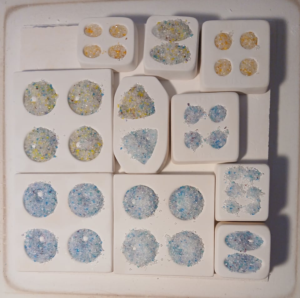 kiln shelf with a variety of molds. the one im most excited about is the one with 50 little round divets for about half inch cabochons and they're in a rainbow