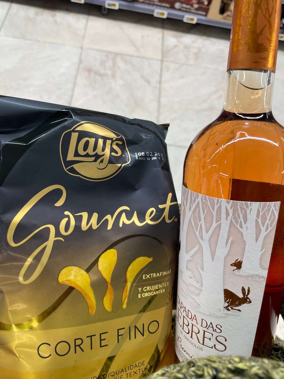 A bag of "Gourmet" potato chips and a bottle of Rose.