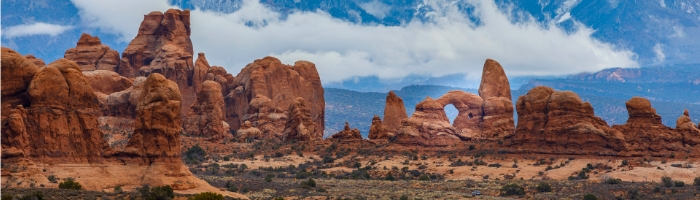 Arches national park, Utah, with cloudy blue skies over red rocks jutting upwards
