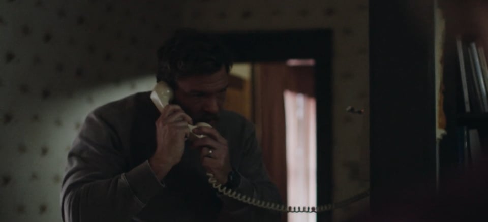 screen cap of the trailer for Ordinary Angels, showing a very large man holding an old style phone handset. It looks like a toy because he's so big