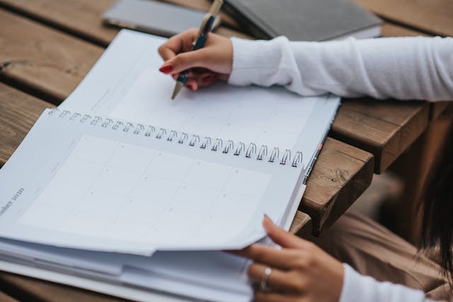 Stock image of a person writing in an open notebook.