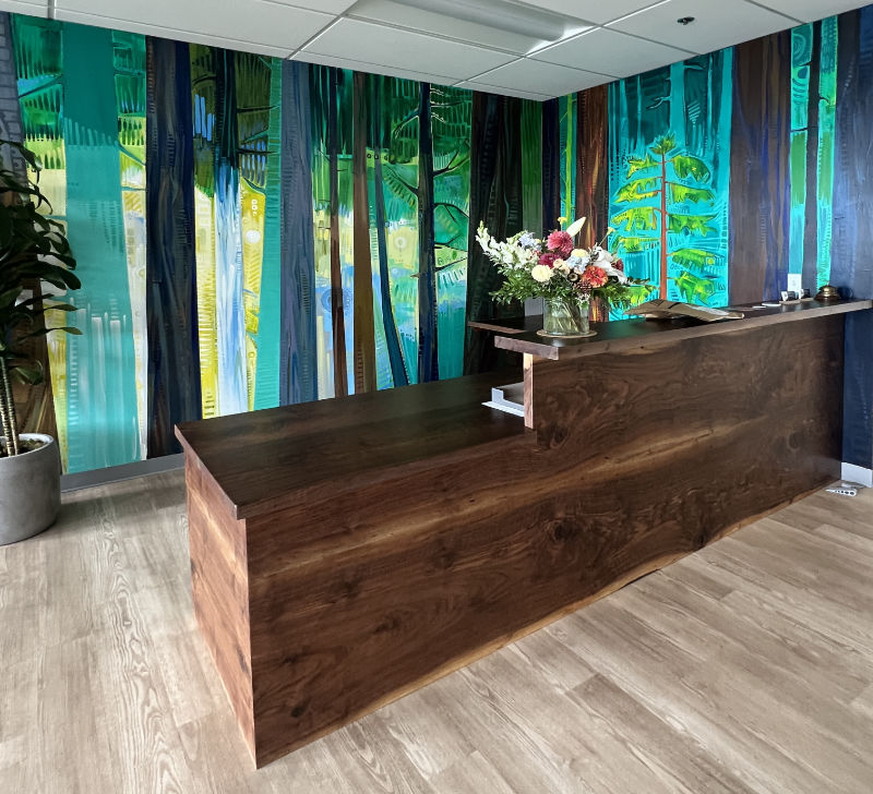 photo d'un comptoir d'accueil avec une fresque murale représentant une forêt en arrière-plan
